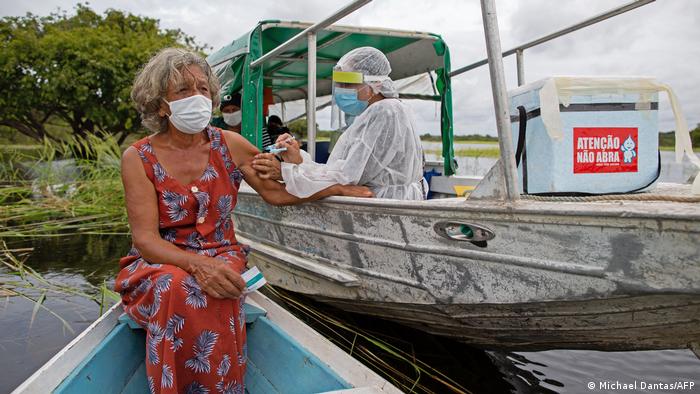 Mujer recibiendo una vacuna en una barca, en Brasil